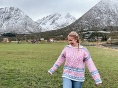 woman in pink Norwegian sweater with mountain backdrop in Lofoten, Norway