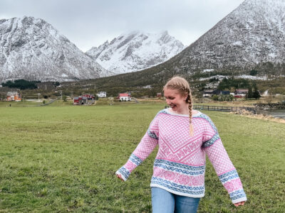 woman in pink Norwegian sweater with mountain backdrop in Lofoten, Norway
