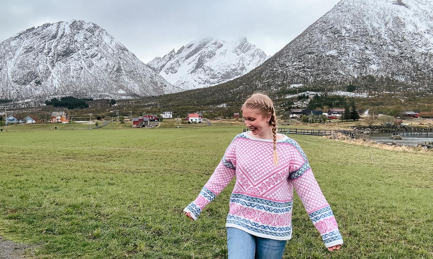 woman in pink Norwegian sweater with mountain backdrop in Lofoten, Norway